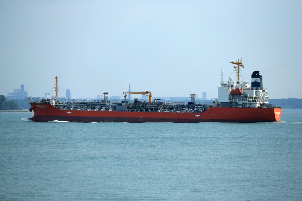 An oil tanker travels through a commercial harbor on a clear day.