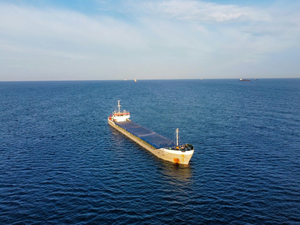 A cargo ship moves through the ocean, captured from above in a seascape scene.